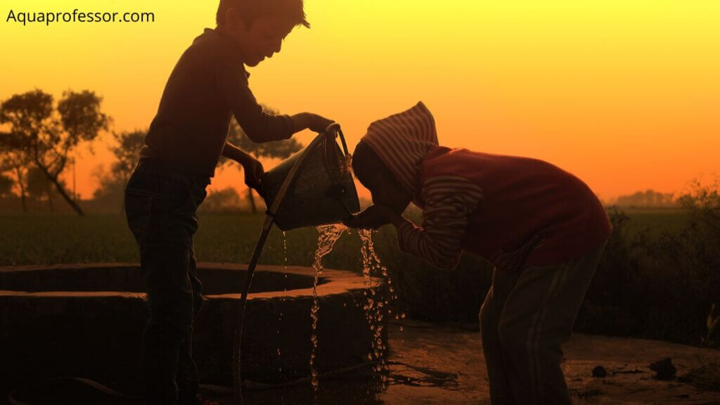 a boy giving water to a girl from well in sunset setting 